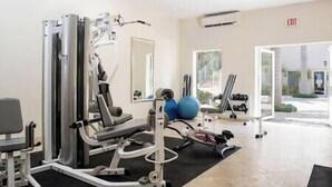 Een sportschool met trainingsapparatuur, een spiegel en uitzicht naar buiten.