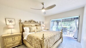 Quarto com cama grande, cabeceira elaborada, duas mesas de cabeceira com abajures e ventilador de teto.