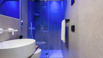 A modern bathroom with a large white sink, a glass-enclosed shower, and a toilet.