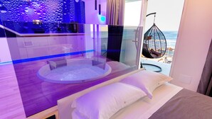 Een moderne kamer met een bed, een zithoek in een cirkelvorm en uitzicht op het strand.