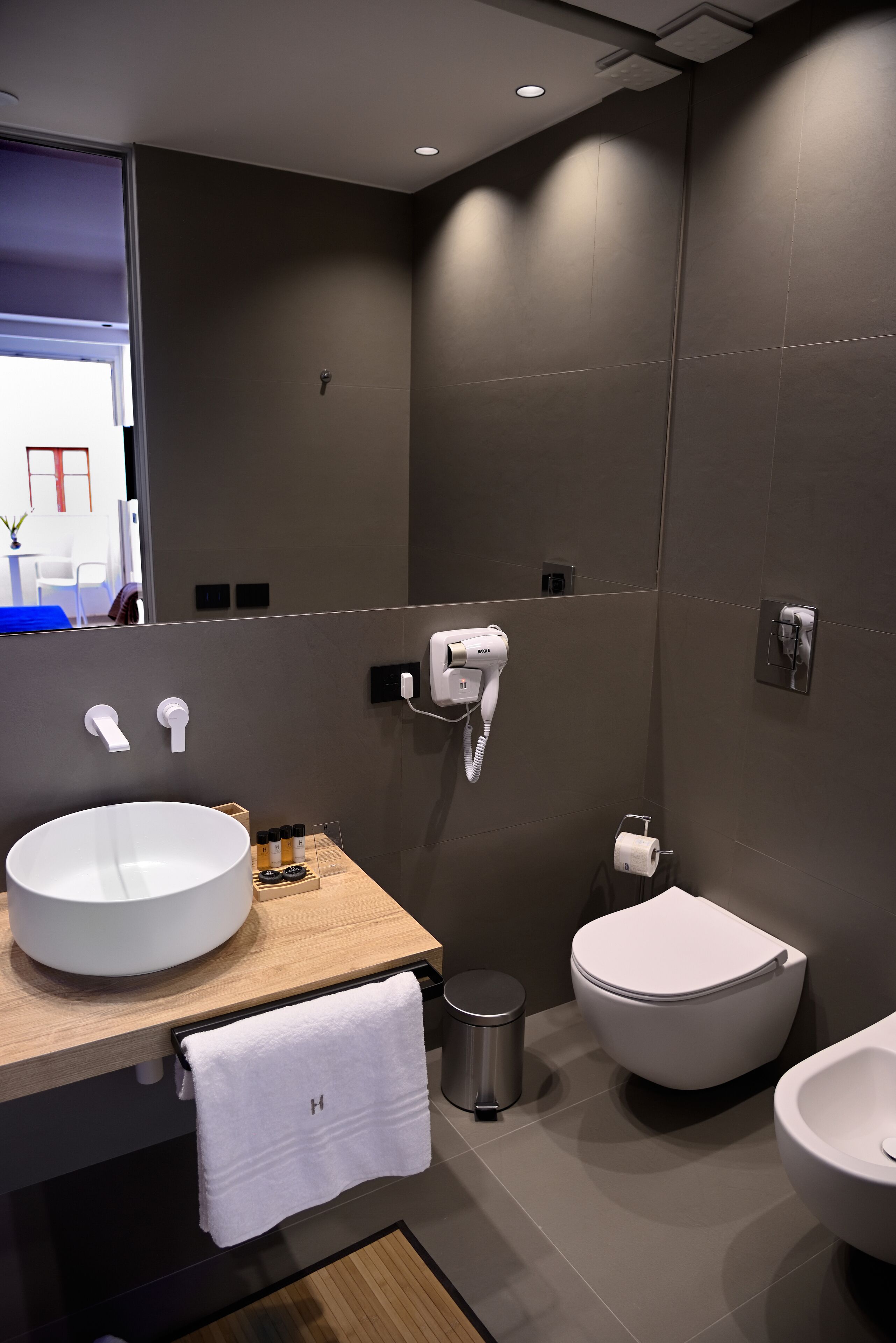 Une salle de bain moderne avec un grand lavabo blanc, des toilettes et un bidet.
