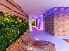 Un corridoio con una panchina in legno, un muro in pietra e un muro verde con piante.