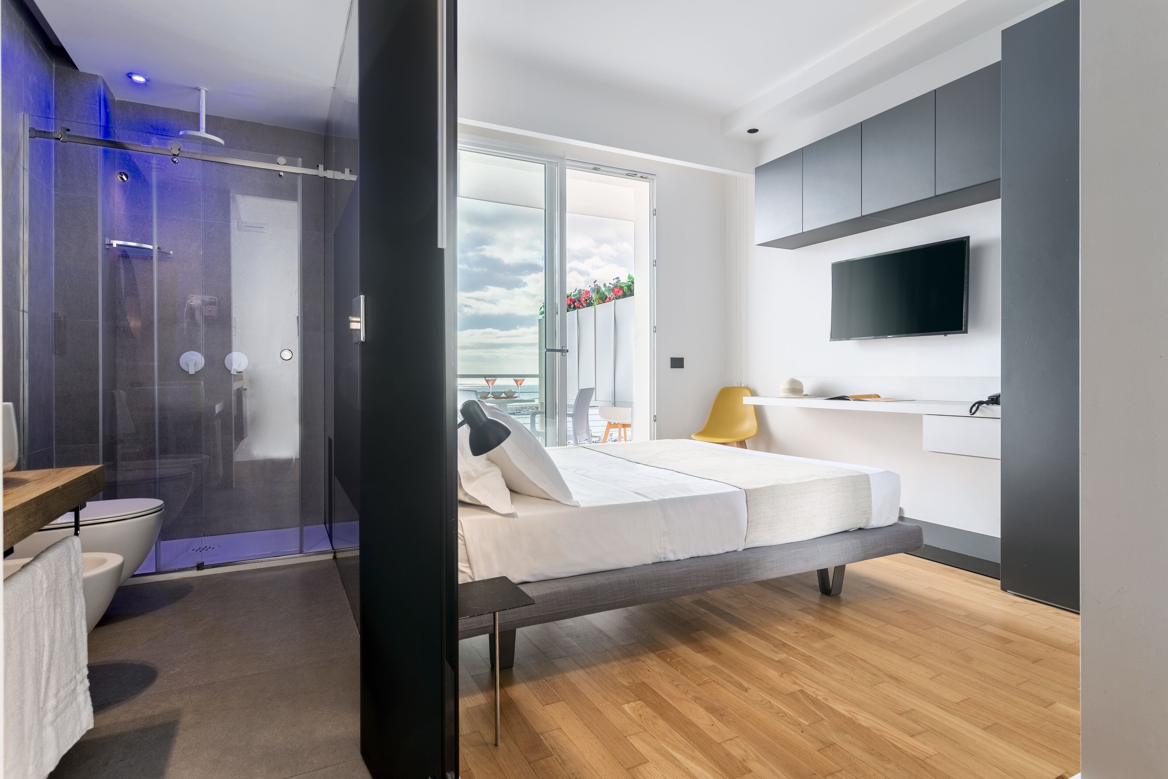Ein modernes Schlafzimmer mit Bett, Fernseher und einem Balkon mit Aussicht.