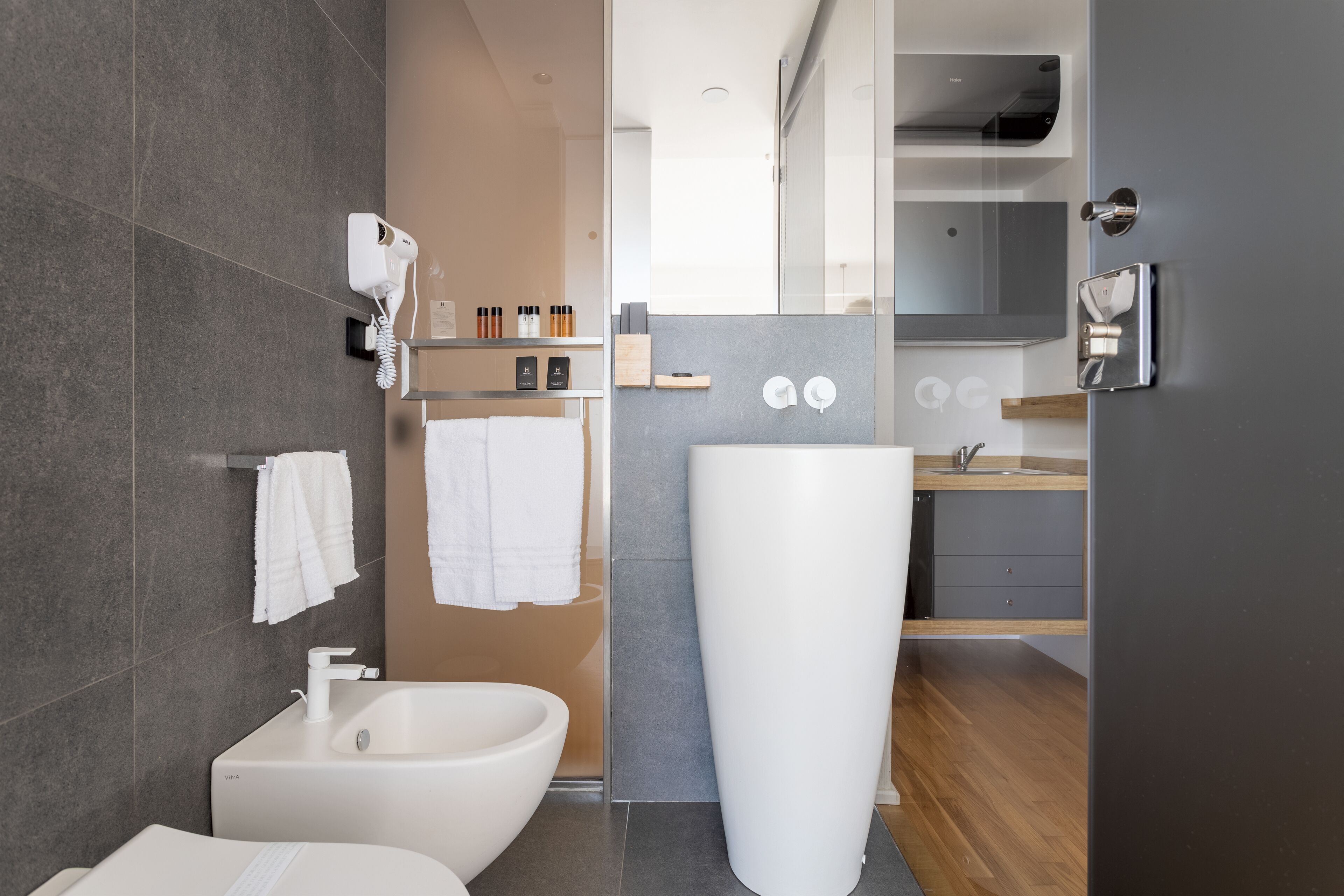 A modern bathroom with a bidet, a large mirror, and a wooden vanity.