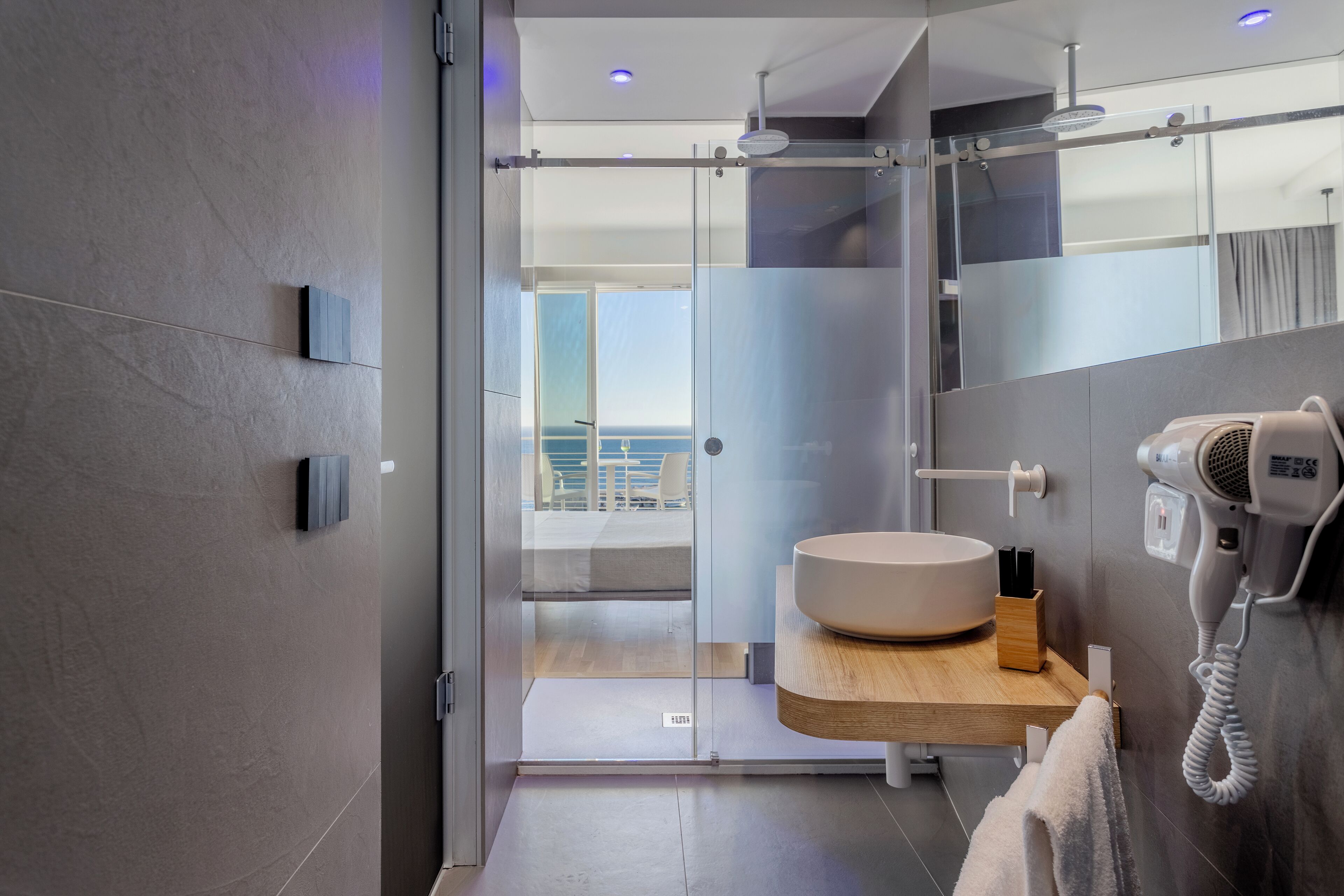 Un baño moderno con un espejo grande, un lavabo redondo y un secador de pelo.