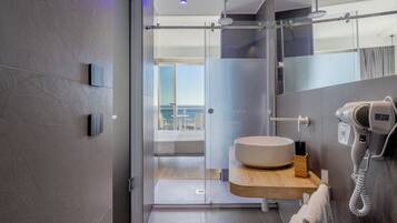 Un baño moderno con un espejo grande, un lavabo redondo y un secador de pelo.