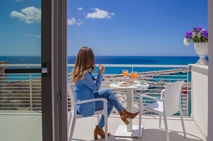 Una donna seduta su un balcone con vista sul mare e sul porto turistico.