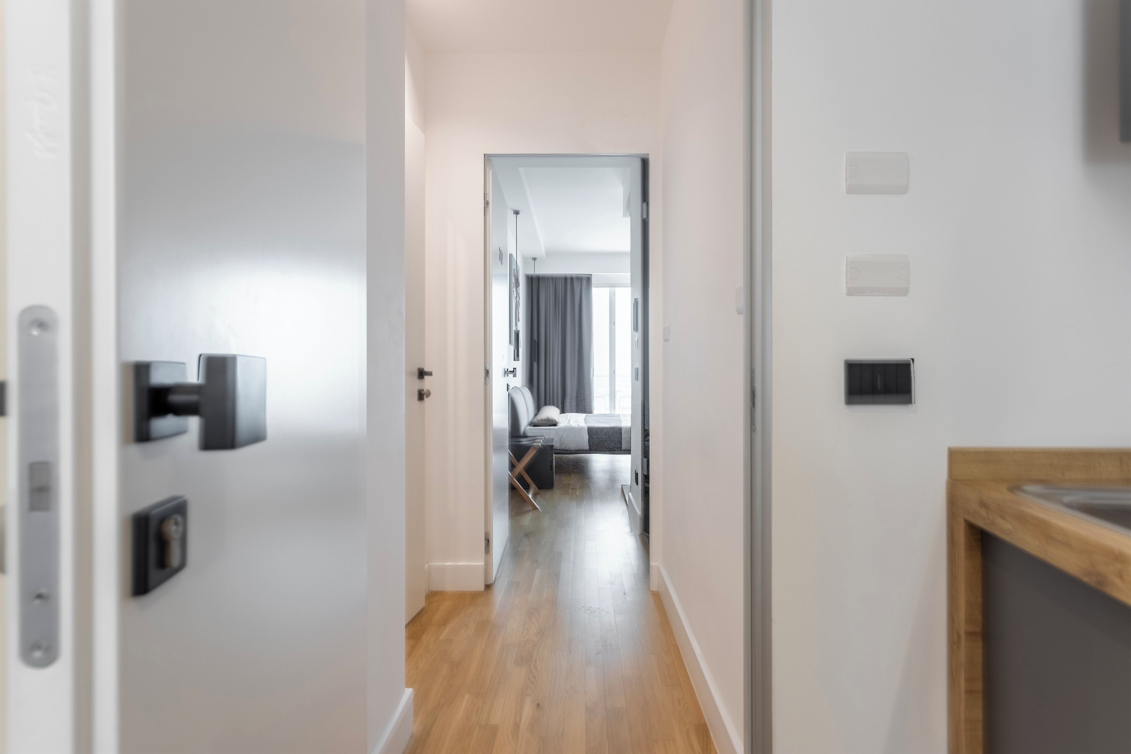 Un couloir menant à une chambre à coucher équipée d’un lit, d’un bureau et d’une chaise.