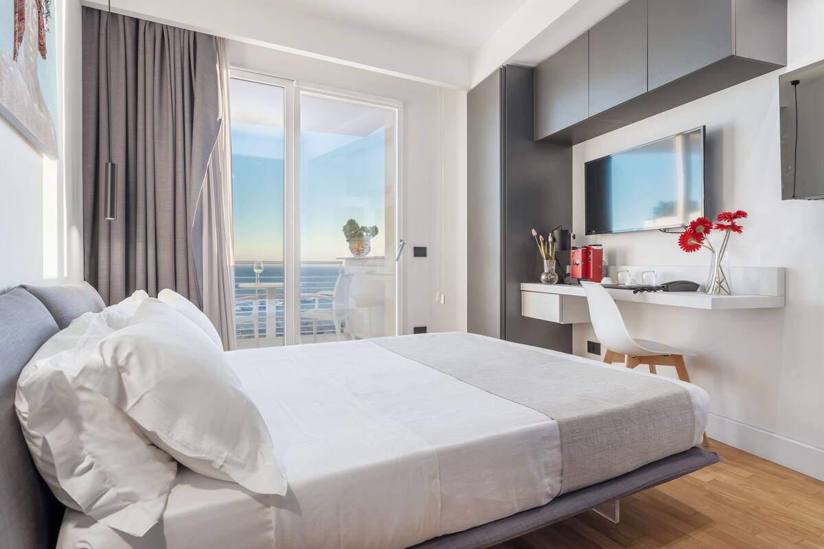 A modern hotel room with a bed, a desk, and a TV.