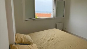 Ein Schlafzimmer mit einem Bett, zwei Kissen, einem Fenster und einer Heizung.