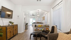 Uma sala de estar moderna com televisão de tela plana, armário de madeira e estante com livros.