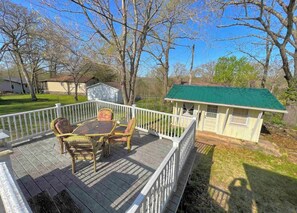 A covered outdoor deck with wicker furniture and a small shed with a green roof. - Spacious, Cozy Lake House near lake and restaurants at Lake of the Ozarks.  (Warsaw)