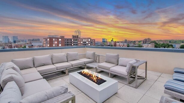 A rooftop terrace with a modern outdoor seating area, a fire pit, and a city skyline view at sunset. - Chic 1 bed Apt + Rooftop & Gym - Downtown Stamford (Stamford)