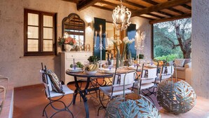 A dining area with a rustic wooden ceiling, a chandelier, and a table set for a meal. - Villa Arsina in Lucca (Lucca)