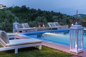 A swimming pool area with lounge chairs and a lantern.