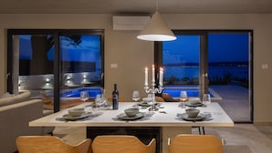 A dining area with a table set for four, a bottle of wine, and candles. - Beachfront Villa Tota with Pool (Kaštel Štafilić)