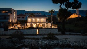 A modern two-story house with a stone wall in front, a small pool, and a view of the sea. - Beachfront Villa Tota with Pool (Kaštel Štafilić)