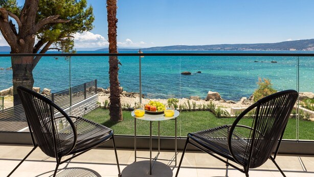 A balcony with two chairs, a small table with fruit, and a view of the sea. - Beachfront Villa Tota with Pool (Kaštel Štafilić)