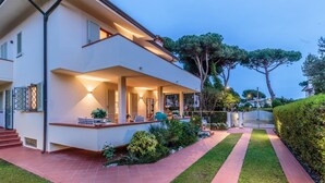 A modern two-story house with a covered porch, a well-maintained lawn, and a pathway leading to the entrance. - Regina Beach Villa by the Beach in Marina di Piet (Camaiore)