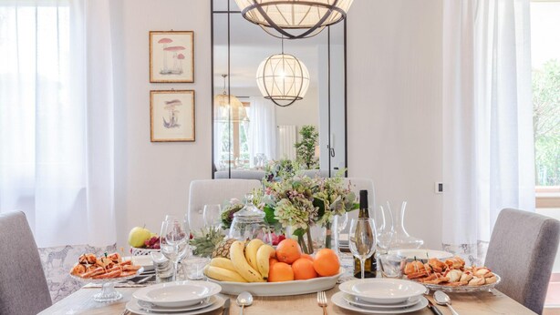 A dining table set for a meal with plates, cutlery, and a fruit platter. - Regina Beach Villa by the Beach in Marina di Piet (Camaiore)