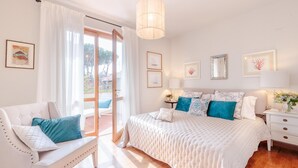 A bedroom with a large bed, a sofa, a nightstand, and a window with curtains. - Regina Beach Villa by the Beach in Marina di Piet (Camaiore)