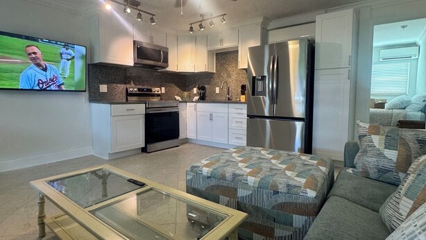 A modern kitchen with white cabinets, a microwave, and a refrigerator.