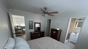 A bedroom with a bed, dresser, mirror, and ceiling fan.