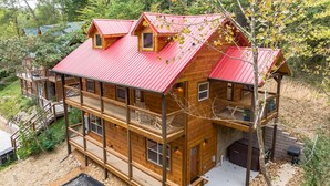 A multi-story wooden cabin with a red roof, a balcony on the upper floor, and a small window on the upper level. - ⛰️Li'l Red Express Cabin in Pigeon Forge🌄Close to Dollywood🎢 & The Island  (Pigeon Forge)