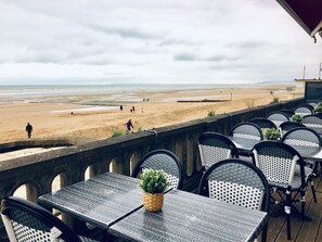 A seaside terrace with tables and chairs overlooking a beach.