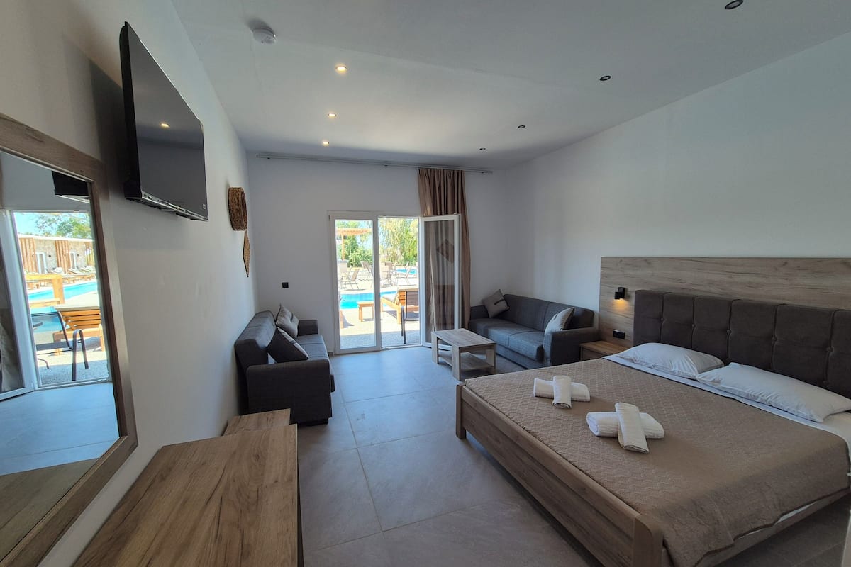 A modern hotel room with a bed, sofa, and a small table.