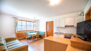 A compact living space with a kitchenette, a dining area with a table and chairs, and a sofa.