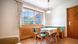A cozy dining area with a wooden table and chairs, a bench, and a window with curtains.