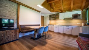 Una cocina moderna con vigas de madera, microondas integrado y una zona de comedor con banco y sillas.