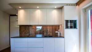 Een moderne keuken met witte kastjes, een houten accentmuur en ingebouwde apparatuur.