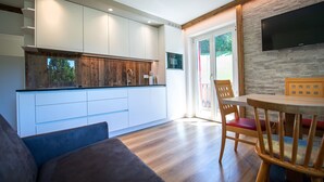 Een moderne keuken met witte kasten, een houten aanrecht en een inbouwoven. Er is een eethoek met een houten tafel en stoelen.