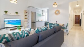 A modern living room with a sofa, TV, and dining area.