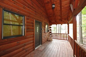 Une cabane en bois avec une véranda, une porte et une fenêtre.