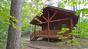 A wooden cabin with a porch, surrounded by trees. - Destiny's Daydream - Couple's Cabin- Hocking Hills (Logan)