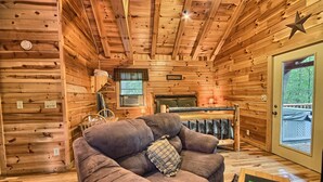 A cozy cabin interior with a sofa, a small table, a window with a view, and wooden walls. - Destiny's Daydream - Couple's Cabin- Hocking Hills (Logan)
