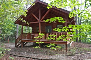 A wooden cabin with a porch and a staircase leading to the entrance.