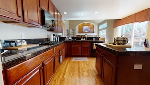 A kitchen with wooden cabinets, a black countertop, and a central island.
