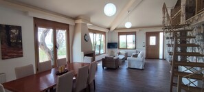 Relax in this spacious living area with a high ceiling, featuring a dining table, sofa, and TV.