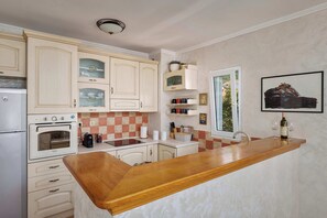 Une cuisine dotée d’un plan de travail en bois, de meubles blancs, d’un four encastré et d’une fenêtre offrant une vue agréable.