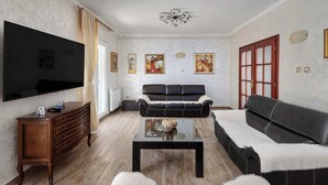 Una sala de estar con una televisión de pantalla plana, un sofá, una mesa de centro y un mueble.