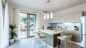 Une cuisine moderne dotée d’un îlot central, de tabourets de bar et offrant une vue sur l’extérieur.