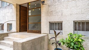 A stone building with a wooden door, concrete steps, and potted plants.