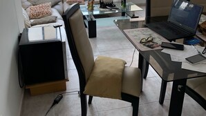 Un salon moderne avec un canapé, une table basse en verre, un ordinateur portable et un téléviseur.