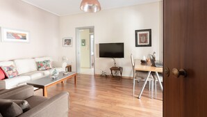 Ein Wohnzimmer mit einer Couch, einem Couchtisch und einem Fernseher an einer Holzwand.