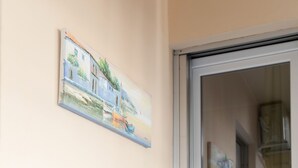 Ein Zimmer mit zwei schwarzen Stühlen und einem kleinen weißen Tisch, einem Bild an der Wand und einer Schiebetür zu einem anderen Raum.