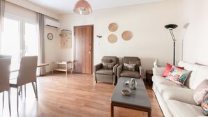 Ein modernes Wohnzimmer mit einer Couch, Sesseln, einem Couchtisch und einem Essbereich mit Stühlen und einem Tisch.